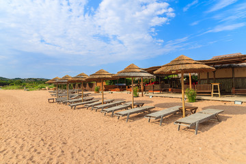 Sunbeds with umbrellas on sandy Santa Manza beach, Corsica island, France