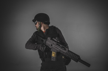 Fototapeta premium airsoft player with gun, helmet and bulletproof vest on gray bac