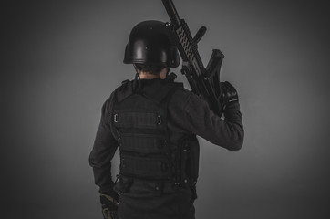 airsoft player with gun, helmet and bulletproof vest on gray bac