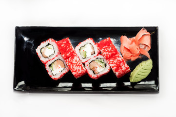 Red tobiko sushi roll platted on a black plate.