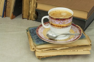 Porcelain cup of coffee and old books. Relax over coffee. Reading old books.
