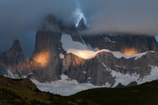 Spots of light on the mountain in the cloud. Mount Fitz Roy. Patagonia. Argentina.