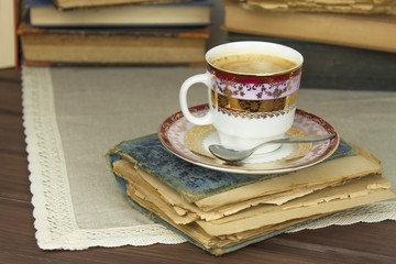 Porcelain cup of coffee and old books. Relax over coffee. Reading old books.
