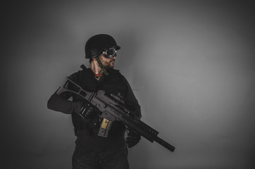 airsoft player with gun, helmet and bulletproof vest on gray bac