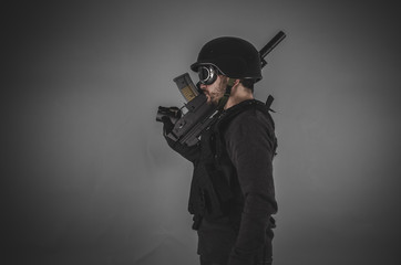 Fototapeta premium guard, airsoft player with gun, helmet and bulletproof vest on g