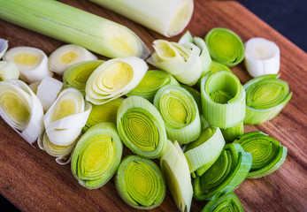 Fresh leeks whole and sliced on a wooden kitchen board