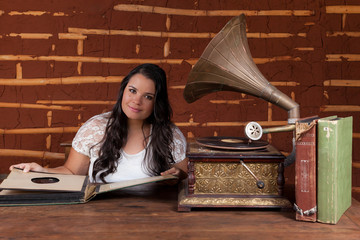 A girl listening to music on an old gramophone with some album d
