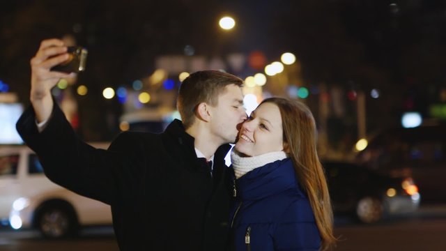 Young couple photographing self against the backdrop of the city at night