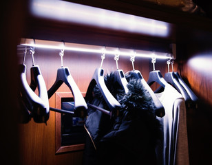 clothers hanging on coat hanger in brown wardrobe