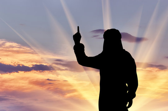 Silhouette of man with hand gesture standing against cloudy sky during sunset
