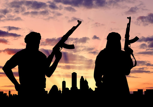 Silhouette of men with rifle in front of city during sunset