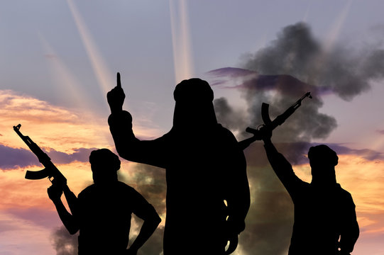 Silhouette of men with rifles against cloudy sky during sunset