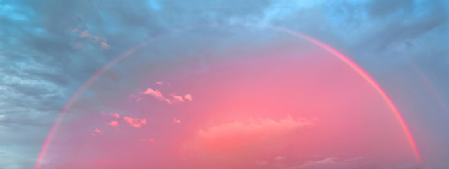 Pink rainbow on sunset sky