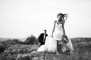 Young newly married couple chasing each other in field
