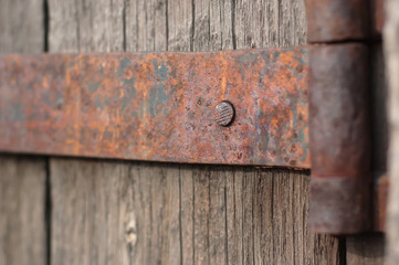Rusty hinge and fragment of old wooden door shallow depth of field