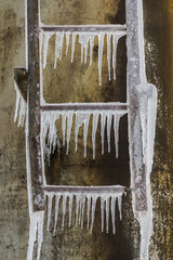 Pointy icicles hang down from rusty iron ladder
