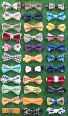 Set of homemade bow ties on green background.