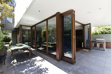 Bi fold doors opening to rear courtyard of contemporary home - obrazy, fototapety, plakaty