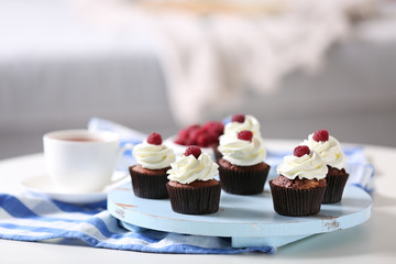 Beautiful chocolate cupcakes with cream and raspberry on table