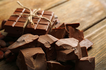 Chocolate pieces, shavings and cocoa beans on color wooden background