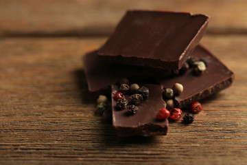 Black chocolate pieces with pepper on wooden background