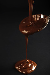Chocolate poured on a spoon on dark background