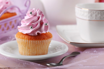 Tasty cupcake on saucer, on light background