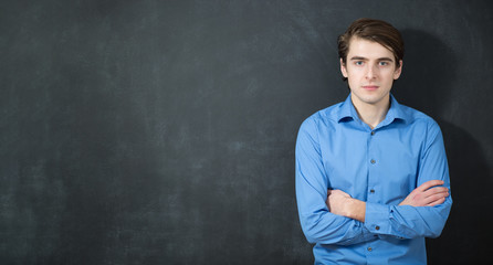 Portrait of a smart young man standing against gray background