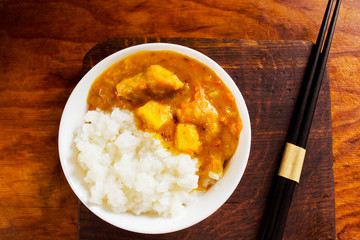 Rice and pork curry in a bowl on a wooden table 