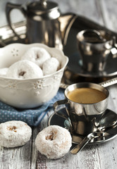 Sweet donuts with icing sugar and cup of coffee