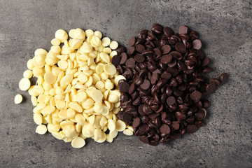 Dark and white chocolate morsels on gray background