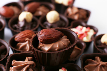 Delicious chocolate candies on white background, close up