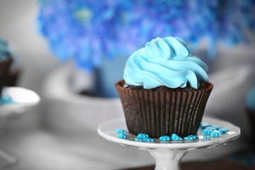 Delicious chocolate cupcake with blue cream on served table, close up