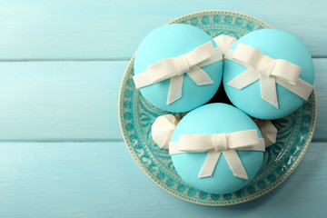 Tasty cupcakes with bow on color wooden background