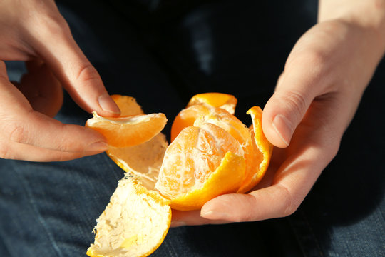 Woman hand peeling ripe sweet tangerine, close up