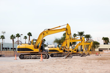 View from side at three excavators machine which stay in one row at a construction site.