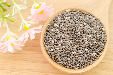 Chia seeds in wooden spoon with flower.