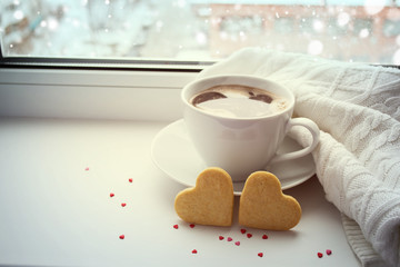 Two sponge heart and a cup of hot coffee on the window. Toning.