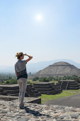 Young woman on top of pyramid covering her eyes from sun overlooking Teotihuacan ruins 