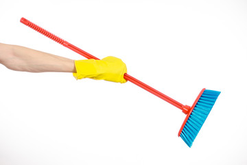 Cleaning the house topic: human hand in yellow rubber gloves holding a red broom isolated on a white background in studio
