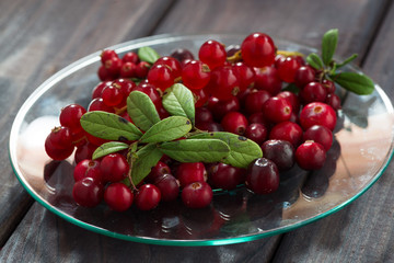 cowberries and red currants in a glass plate on wooden table