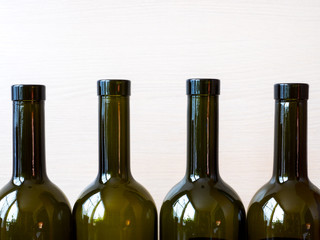 Several wine bottles stands on the table in front of the wooden wall