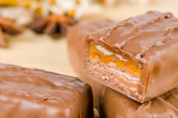 Chocolate bar with caramel toffee on wooden background.