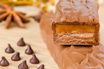Chocolate bar with caramel toffee on wooden background.