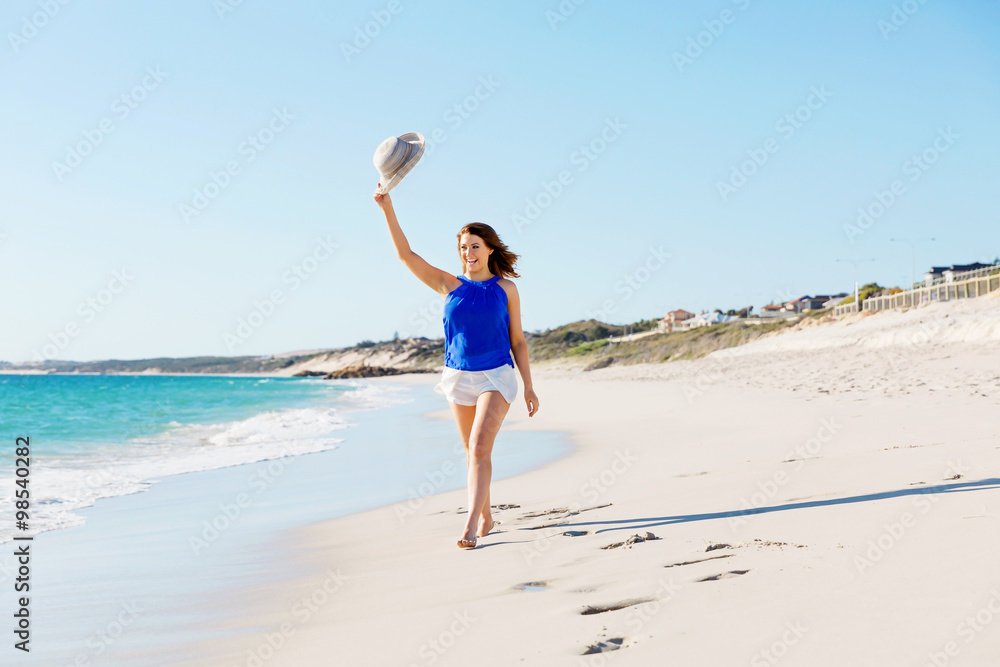 Poster young woman walking along the beach