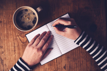 Woman drinking coffee and writing a diary note - obrazy, fototapety, plakaty