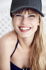 Toothy smile on pretty young woman in cap, portrait