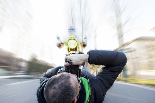 reckless photographer shooting a motorcyclist who is investing