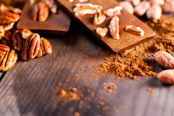 Chocolate products. Chocolate, cocoa beans, cocoa and nuts on wooden background. 