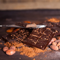 Chocolate products. Chocolate, cocoa beans, cocoa and nuts on wooden background. 